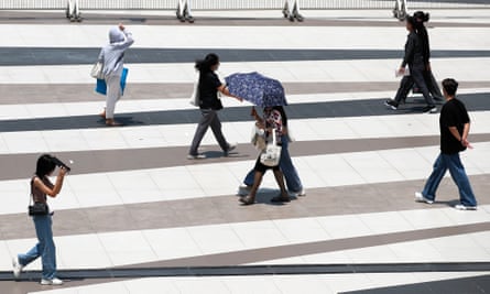 Pedestrians shield themselves from sunlight during hot weather in Bangkok