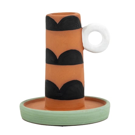 A terracotta coloured candle stick with a black pattern