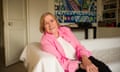 Shirley Conran in sitting room in pink jacket smiling with colourful mural in background