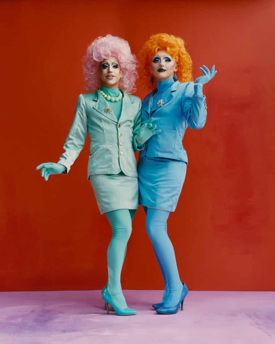 pair in brightly colored drag-style wigs and suits