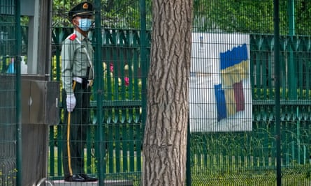 A paramilitary policeman stands guard near a billboard showing a Ukrainian flag at the Romania Embassy in Beijing.
