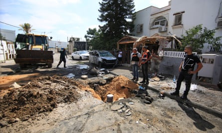 People look at the damage on their street after a rocket attack by Hamas.