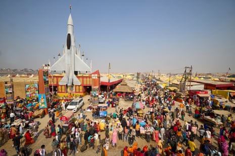 People in front of a tent city, featuring a representation of a space rocket on a makeshift building