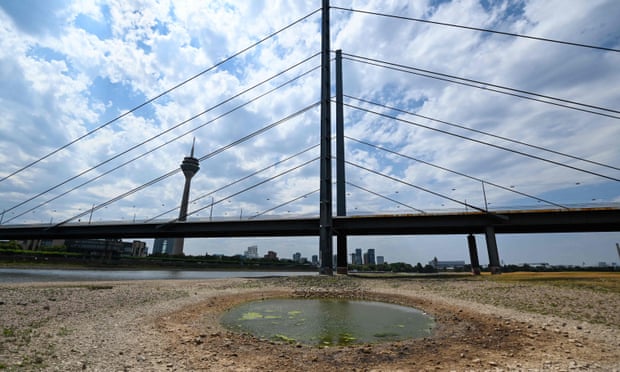 An inland vessel navigates on the Rhine as the partially dried-up river bed is seen in the foreground in Düsseldorf, western Germany.