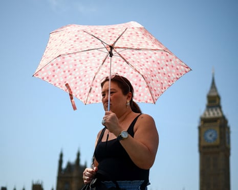 A woman holds a floral umbrella for shade with Big Ben visible in the background