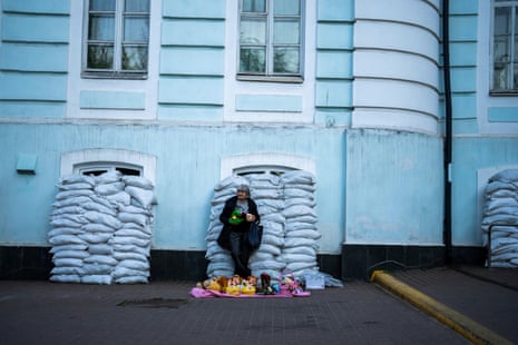 A woman sells toys in front of a building with windows protected by sandbags in Kyiv, Ukraine, on Sunday.