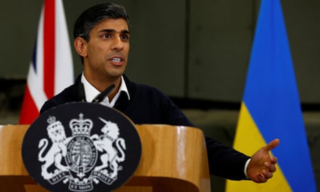 Rishi Sunak gestures as he speaks at a lectern bearing the UK royal coat of arms, in front of the British and Ukrainian flags