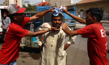 A man attempts to cool off using wet towels at a roadside camp in Karachi