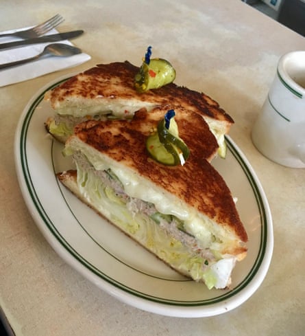 A wedge-shaped toasted sandwich with melted cheese and slices of dill pickle