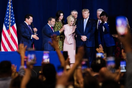 religious leaders on a stage pray over Donald Trump as evangelicals raise their hands in prayer