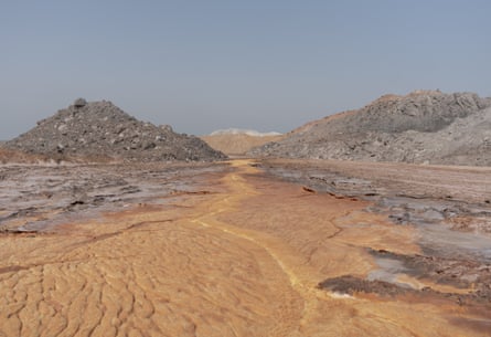 On Hormuz Island, vivid orange mineral-streaked ground winds between grey rocky mounds