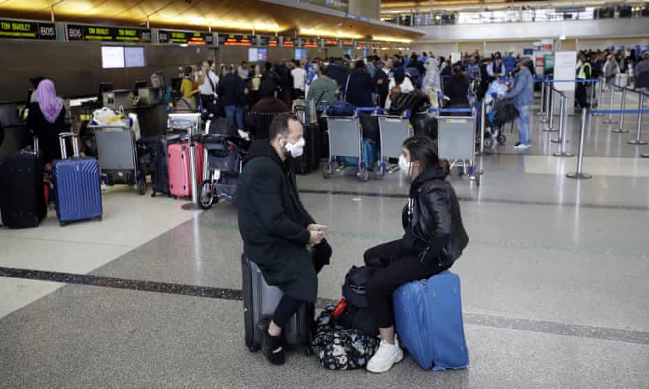 Masked passengers wait to check in at the Los Angeles international airport