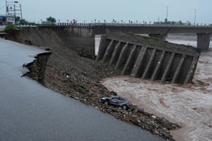 A collapsed section of bridge, with a damaged car visible in the debris