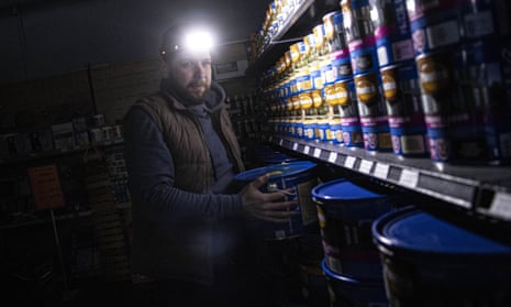 A Ukrainian salesman works in a warehouse with a headlight during a power outage in Kyiv.