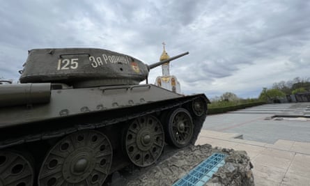 A monument with a Soviet tank with a Christian Orthodox church in the background