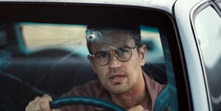 Theo James, as a man wearing glasses, drives a car behind a cracked, bullet-holed windscreen