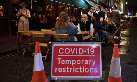 People drinking outside an establishment in Soho in London after dark.