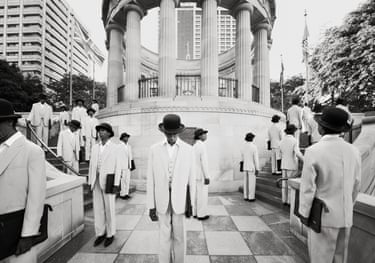 Majority Rule (memorial) 2014. A monochrome photo of repeated images of man in a white suit and a black bowler hat standing in various poses around a memorial shrine.