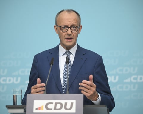 Friedrich Merz gesticulates with both hands behind a lectern