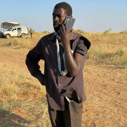 Adam Yagoub in an arid landscape speaking into a cellphone.