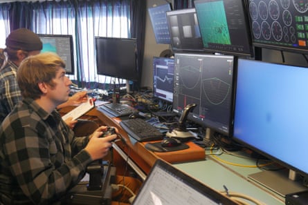 Man uses control stick in front of computer screens