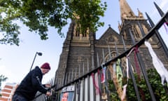 Brian Cherrie ties ribbons to the fence of St. Patrick Cathedral during a mass for Cardinal George Cardinal Pell