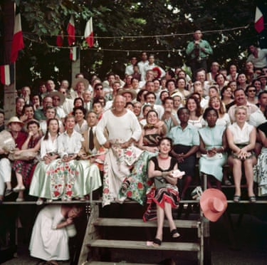 Picasso sits with a coloured cloth over his knees at the front of a crowd at a bullfight