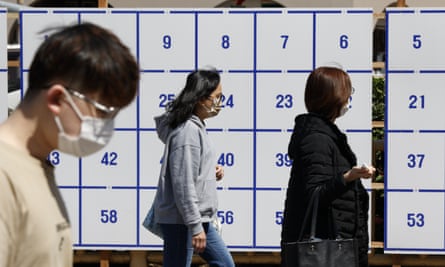 Pedestrians in Tokyo walk past a poster board for the coming local elections