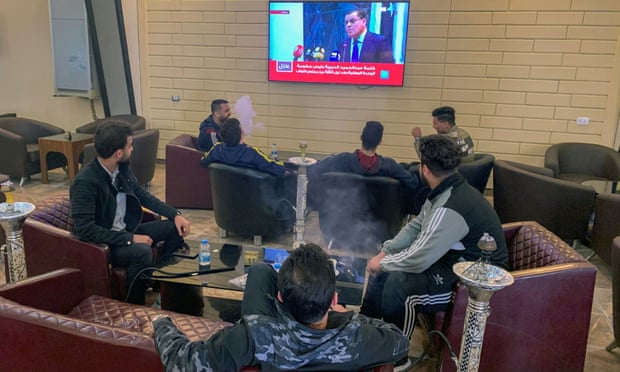 People watch Libya’s newly-elected prime minister Abdelhamid Dbeibah speaking on a TV screen at a cafe in Misrata