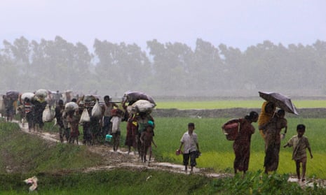 Rohingya refugees from Rakhine state in Myanmar walk along a path in the rain