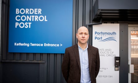 Mike Sellers stands outside another part of the new building by a blue sign saying ‘Border Control Post’.