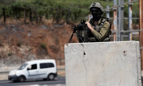 An Israeli soldier rests a gun on a concrete block