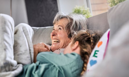 Grandmother lying next to her granddaughter on a sofa at home