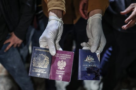 Gloved hands holding three passports of officials killed in Gaza while working at the US-based international volunteer aid organization World Central Kitchen