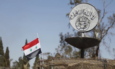 A Syrian national flag flutters next to the Islamic State’s slogan