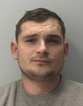 A mug shot of a white man with short brown hair wearing a grey tracksuit.