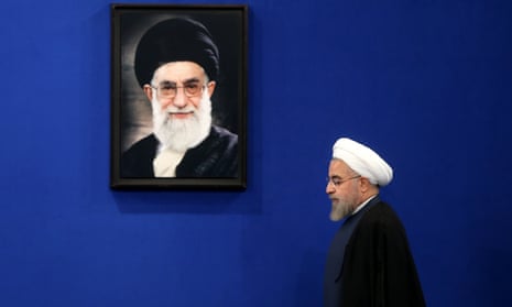 The Iranian president, Hassan Rouhani, walks under a picture of the supreme leader, Ayatollah Ali Khamenei