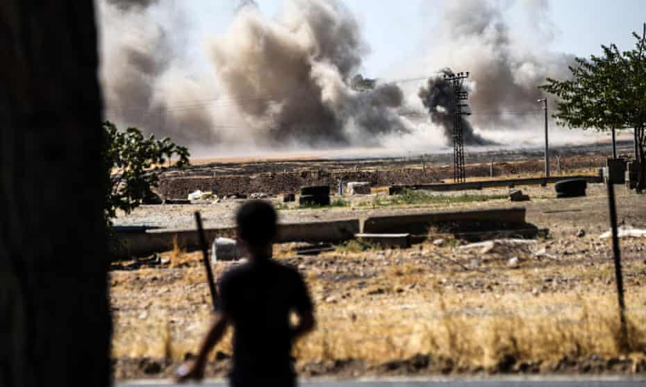 A boy looks on as smoke rises close to the Syrian-Turkish border town of Jarabulus