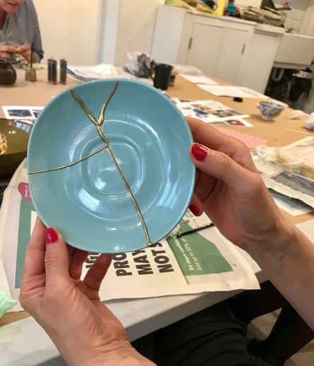 A person holds up a plate that has been mended using the kintsugi technique.