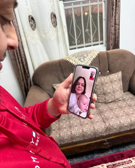 Awad holds a phone on which McMyler and the baby Taj can be seen