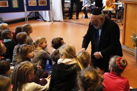 rabbi kneels to speak to kids