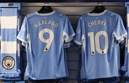 Manchester City shirts for Haaland and Cherki hang on display hooks in a shop