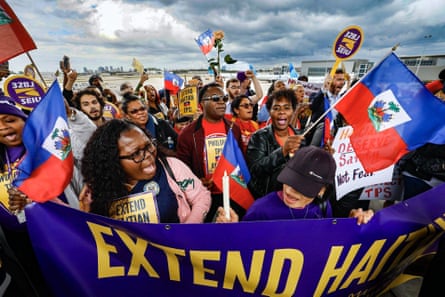 people hold signs that read ‘extend Haitian TPS’