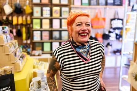Woman in stripy black and white top with dyed-orange hair in her shop