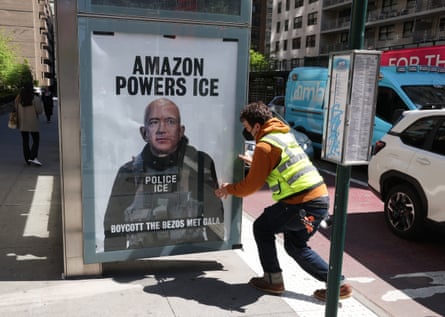 A man in high vis puts up a ‘Boycott the Bezos Met Gala’ poster at a bus stop in Manhattan on 27 April.
