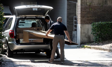 Two FBI agents putting a painting in the back of a car