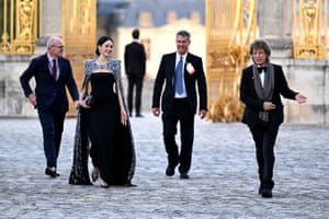 Melanie Hamrick, in a long black dress, and Mick Jagger, wearing a suit, with two men in suits in the background