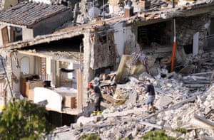 Members of an emergency team walking on the rubble of collapsed buildings in Pescara del Tronto
