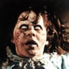 Regan, from The Exorcist, with pale scarred skin and white eyes, stares upward