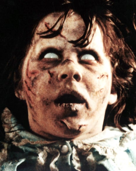 Regan, from The Exorcist, with pale scarred skin and white eyes, stares upward